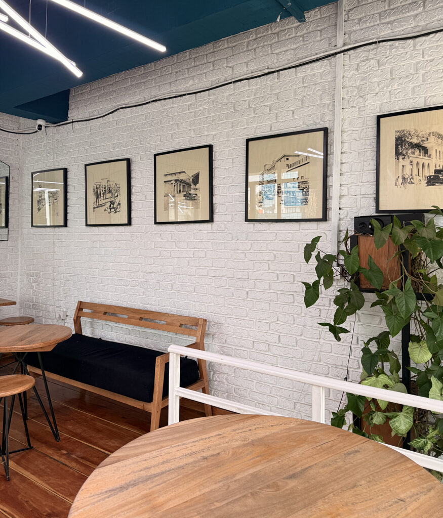 Interior of Rare Coffee café featuring wooden chairs, brick walls, and classic framed artwork